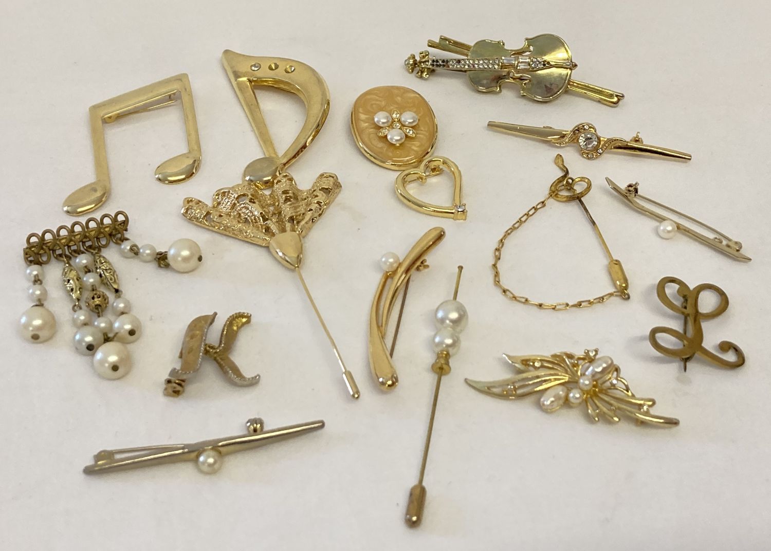 16 vintage and modern gold tone brooches and scarf clips in varying designs.