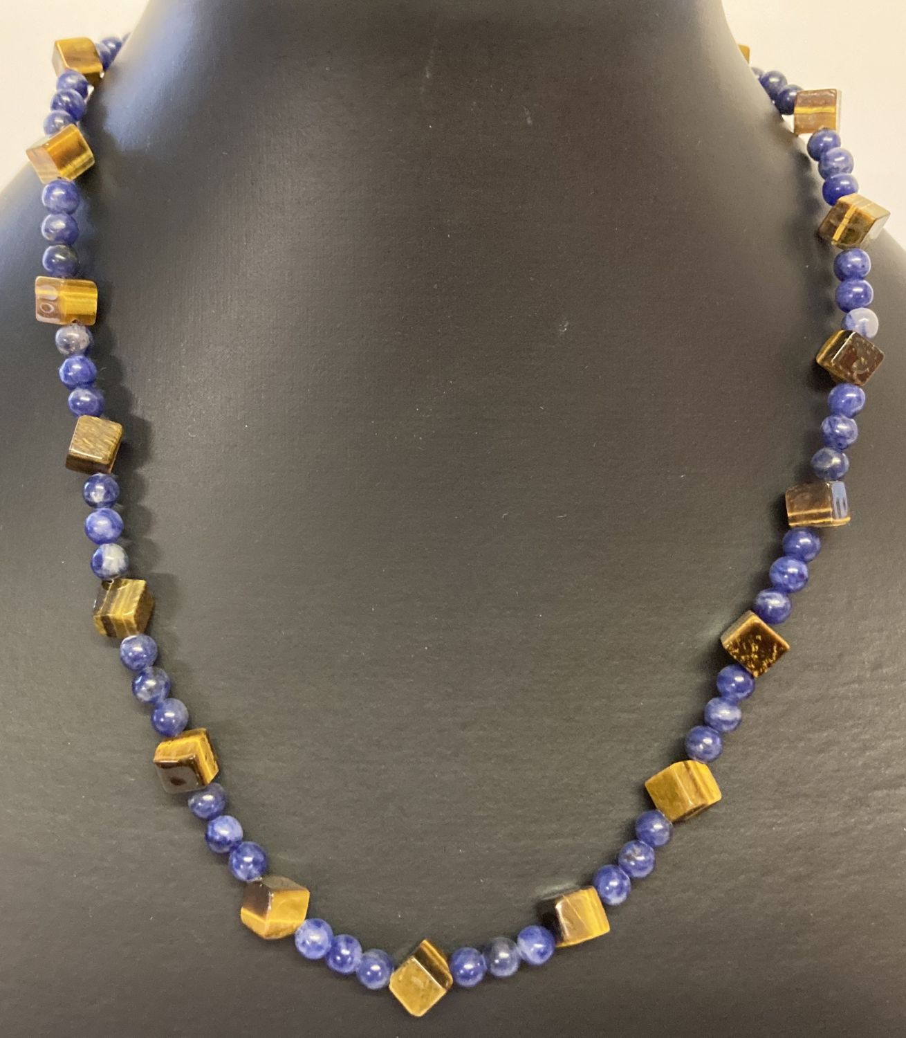 A lapis lazuli and square shaped tigers eye beaded necklace with flower shaped T bar clasp.