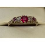 An 18kt gold vintage style ruby and diamond dress ring with scroll and floral design to mount.