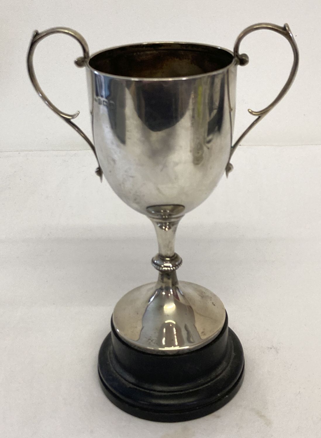 A vintage silver trophy cup on a black wooden stand. Hallmarked William Adams Ltd, Birmingham 1929.