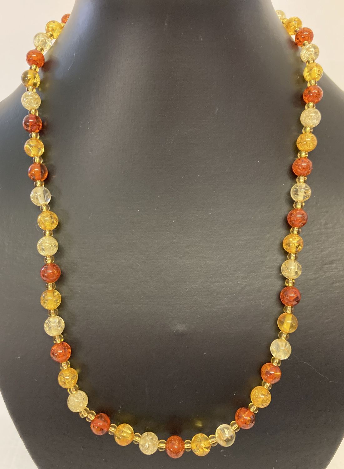 A 22" three coloured faux amber beaded necklace with gold tone T bar clasp.