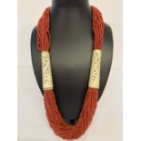 A large coral and natural bone statement necklace with button clasp.