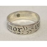 A silver band ring engraved "amor vincit onmia", love conquers all, with engraved floral detail.