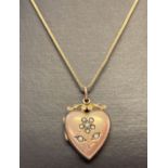 A vintage 9ct gold heart shaped locket set with seed pearls in a floral design.