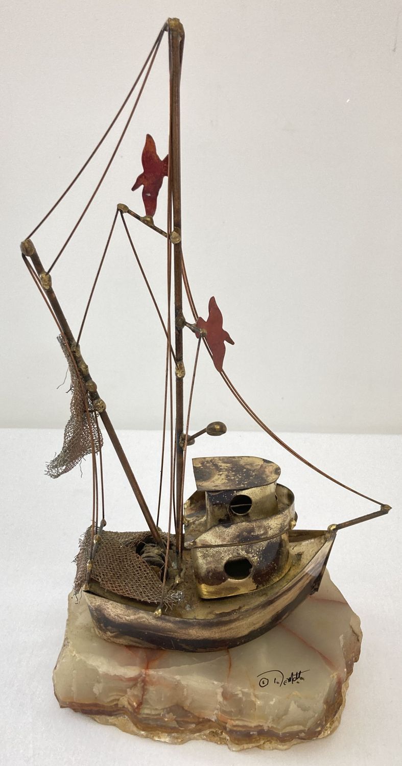 A Demott brass tug boat sculpture with seagull and fishing net detail on a pale green onyx base.