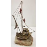 A Demott brass tug boat sculpture with seagull and fishing net detail on a pale green onyx base.