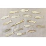 16 mother of pearl games counters in the shape of fish together with one other.