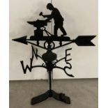 A black cast metal weather vane with blacksmith detail finial to top.
