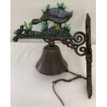 A painted cast iron wall hanging garden bell with duck and duckling detail.