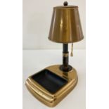 A vintage metal cigarette dispenser in the shape of a table lamp with ashtray.