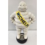 A large painted cast iron Michelin figure of a Michelin man standing on a tyre.