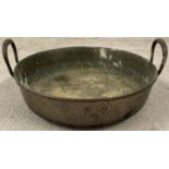 An antique brass two handled shallow pan with rivet detail to handles.