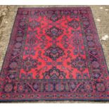 A large vintage wool rug in traditional design. Red ground with blue, green, teal and orange detail.