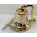 A large brass wall mountable bell with rope handle.