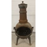 A cast iron garden pot belly style chiminea with ring handles and grilled front door.