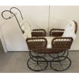 A reproduction double ended black metal and wicker body dolls pram with floral ceramic handle.