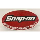 A painted cast metal oval shaped Snap-On Tools wall plaque, in red, black and white.