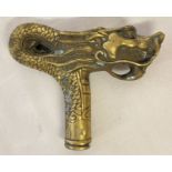A brass walking cane handle in the shape of a dragon.