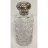A modern silver topped glass scent bottle with floral design to lid.
