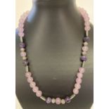 A 20" pink jade and amethyst necklace with white metal decorative beads and S shaped hook clasp.