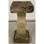 A square shaped 3 sectional pedestal style stone bird bath with carved urn detail to all four sides.