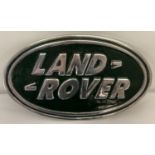 An oval shaped, painted aluminium, Land Rover plaque with wall hanging hook to reverse.