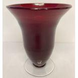 A large red art glass wide rimmed vase raised on a clear glass footed base.