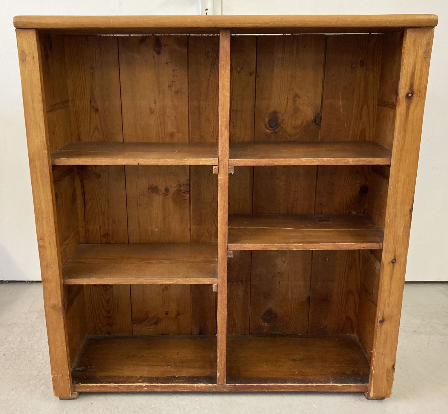 A pine storage unit/bookcase with 4 shelves at varying heights.