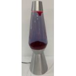 A very large lava lamp with brushed aluminium effect casing and red coloured wax.