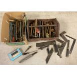 A wooden tool crate with carry handle containing an assortment of mostly carpenters tools.