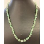 A green aventurine round beaded necklace with white metal spacer beads and T bar clasp.