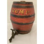 A vintage red and black painted stoneware rum barrel with original brass tap.