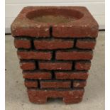 A vintage red and black painted brick design cement garden planter with drainage hole.
