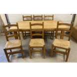 A large solid wood beach dining table and 6 rush seat wooden chairs, wear to some seats.