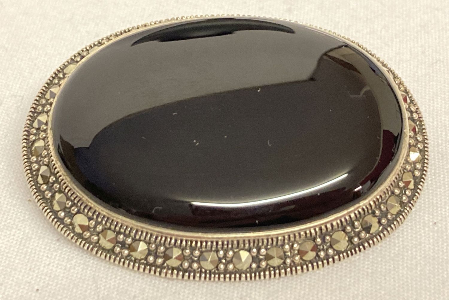 A silver pendant/brooch set with onyx and marcasite stones.