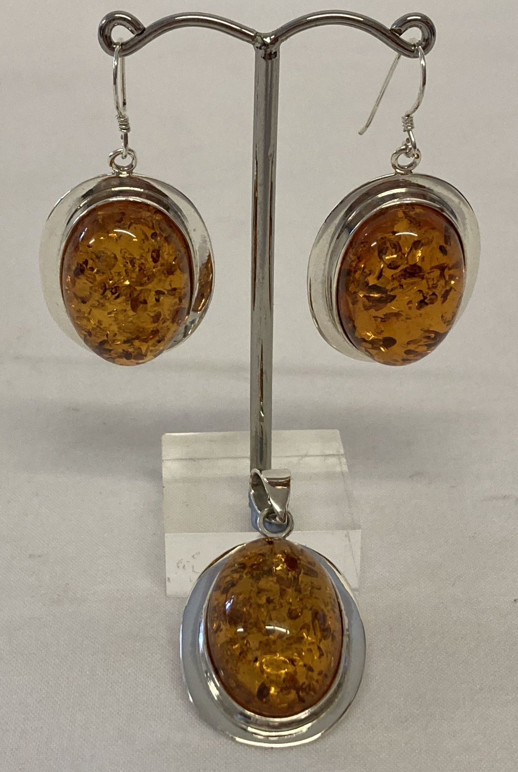 An oval shaped faux amber pendant and matching earrings in 925 silver mounts.