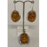 An oval shaped faux amber pendant and matching earrings in 925 silver mounts.