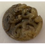 A Chinese Jade carved roundel depicting mythical creatures.