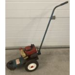 A vintage 1970's petrol push strimmer on wheels with a Tecumseh engine.