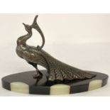 An Art Deco spelter figurine of a peacock mounted on an oval shaped marble and onyx base.