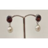 A pair of 9ct white gold, garnet and pearl drop style earrings.