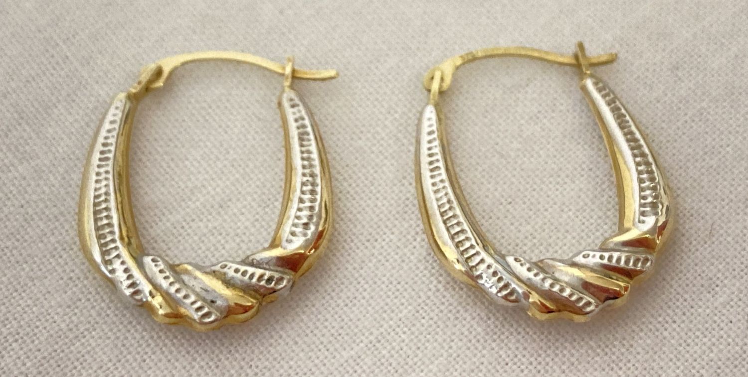 A pair of yellow and white gold twist design hoop style earrings.