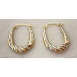 A pair of yellow and white gold twist design hoop style earrings.