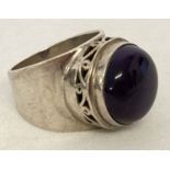 A modern design silver statement dress ring set with a large amethyst round cut cabochon.