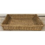 A vintage wicker rectanglur shaped bread basket with carry handles.