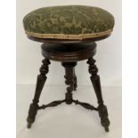A Victorian screw top piano stool with green upholstery seat and carved legs and supports.