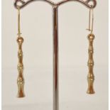 A pair of gold bamboo design drop style earrings.