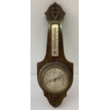 A vintage oak framed wall barometer with carved detail and integral thermometer.