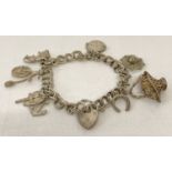 A vintage double curb chain silver charm bracelet with padlock clasp, safety chain and 7 charms.