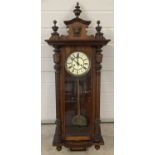 A Victorian German wooden cased wall hanging clock with carved wooden plinth and finial decoration.